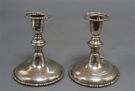 A pair of silver dwarf candlesticks, crested, marked rubbed, one a.f. to top (dented and lead repair), height 13.5cm, weighted.